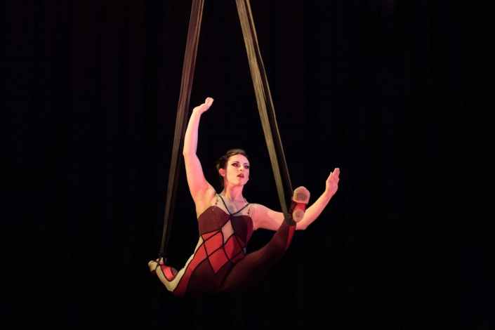 photo of a woman performing a split on aerial straps
