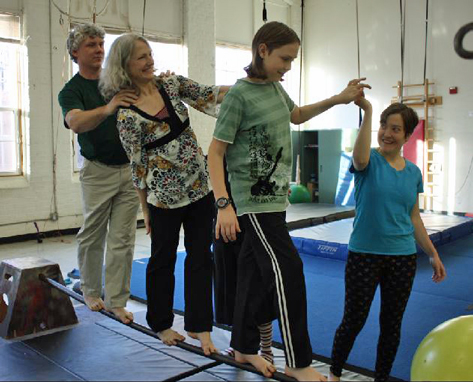 necca-vermont-arts-council-march-2015-FEAT NECCA coach helping a family of three walk across a balancing pipe