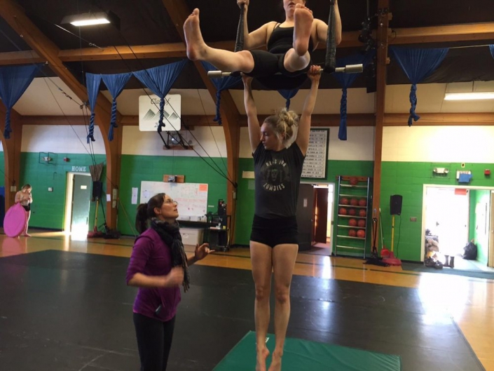 photo of two ProTrack Program students training with a coach on duo trapeze