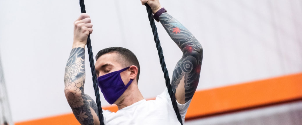male aerialist holding onto dance trapeze ropes