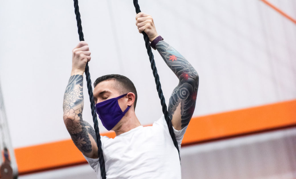 male aerialist holding onto dance trapeze ropes